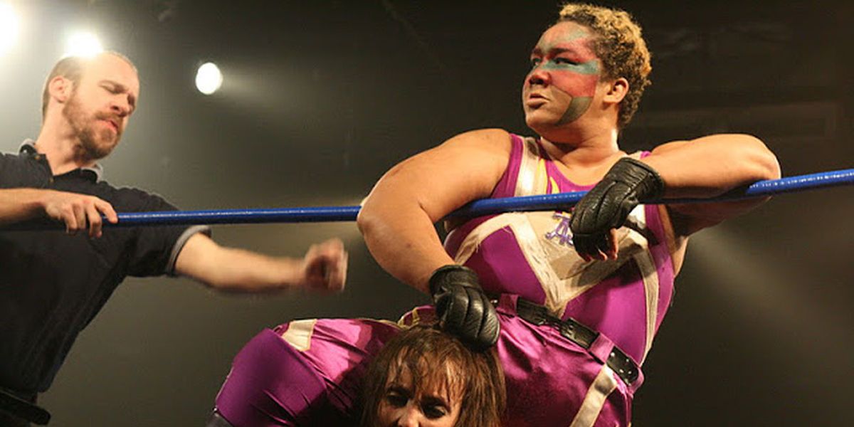 Aja Kong holding opponent's hair next to the referee