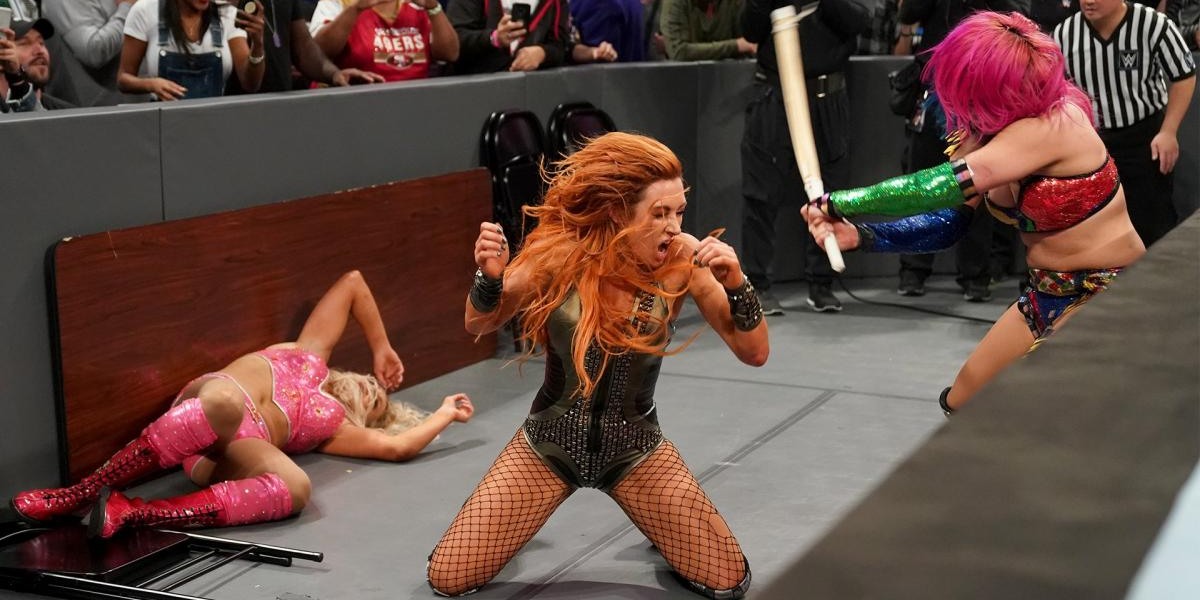 Asuka hits Becky Lynch with a kendo stick as Charlotte lays on the ground
