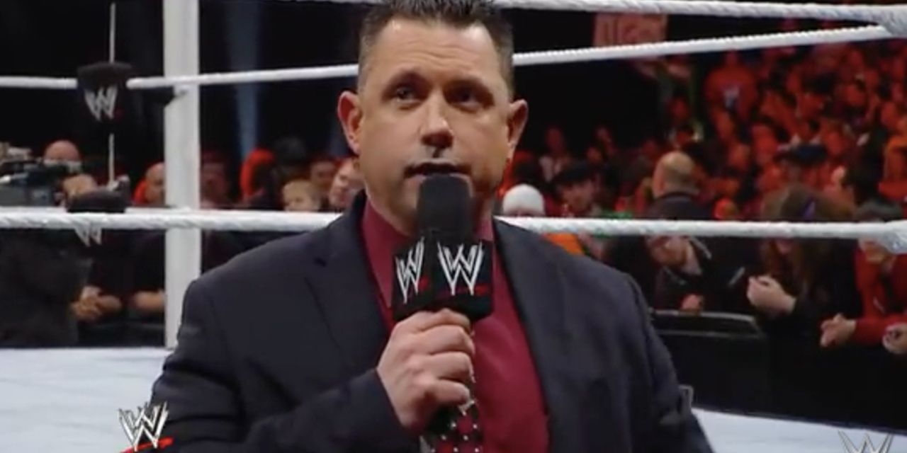 Michael Cole standing ringside with a microphone