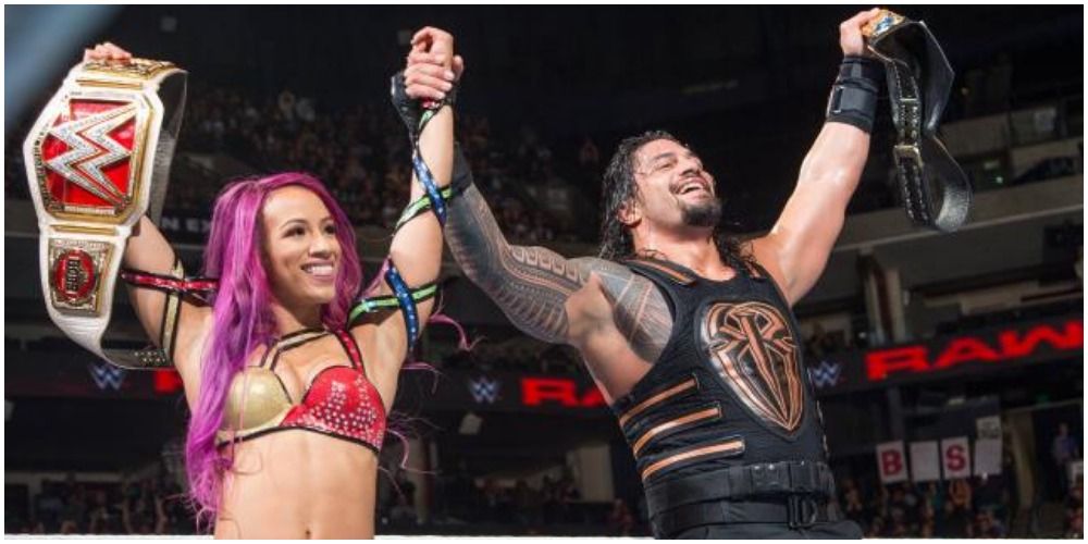 Sasha Banks and Roman Reigns holding belts