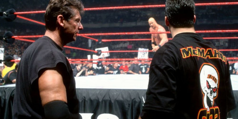 Vince and Shane McMahon looking at Steve Austin from outside the ring.