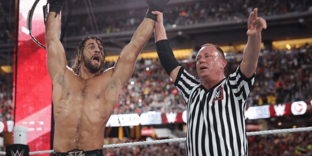 Mike Chioda raising Seth Rollins' hand in victory.