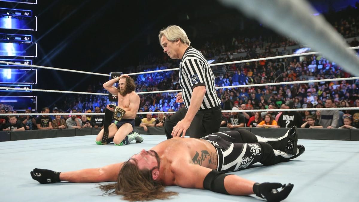 WWE Daniel Bryan Holding The WWE Championship; AJ Styles Lies Motionless