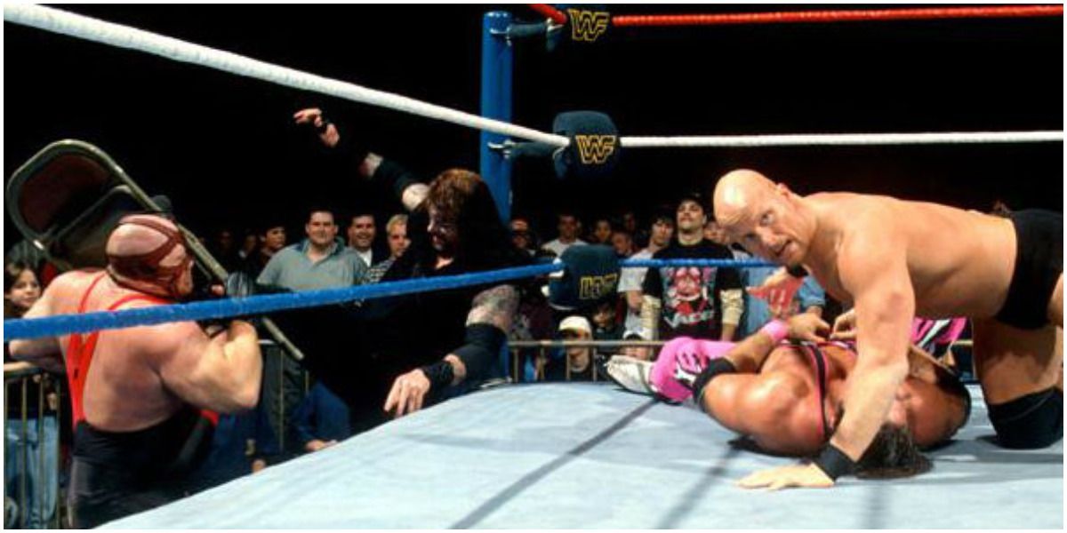 Stone Cold hits Bret Hart on the ground while Undertaker boots a chair into Vader's face at Final Four