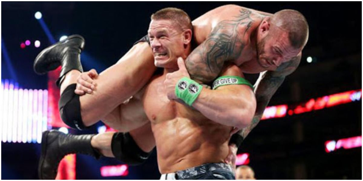 WWE John Cena Giving A Thumbs Up With Randy Orton On His Shoulders