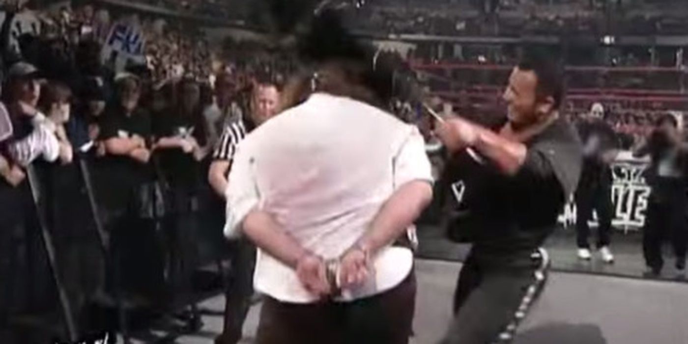 The Rock bashes Mick Foley with a chair.