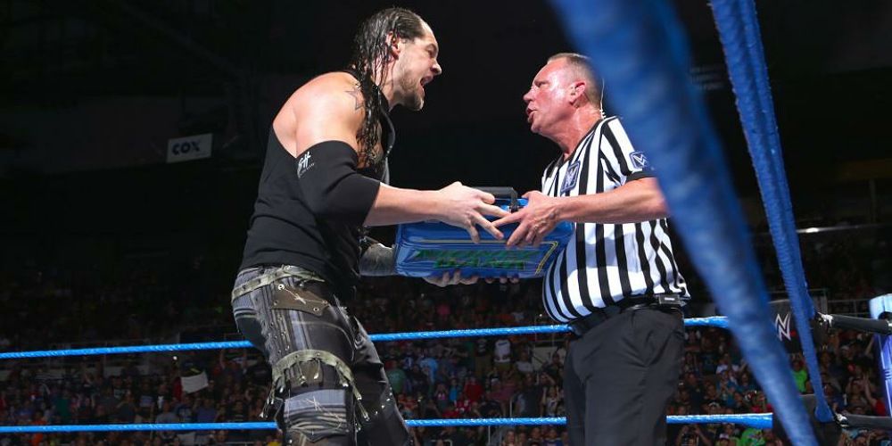 Baron Corbin handing the referee his Money In The Bank contract.