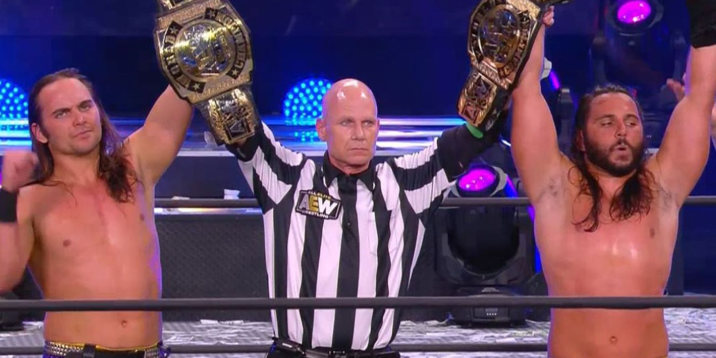 The Young Bucks holding up the AEW tag team titles.