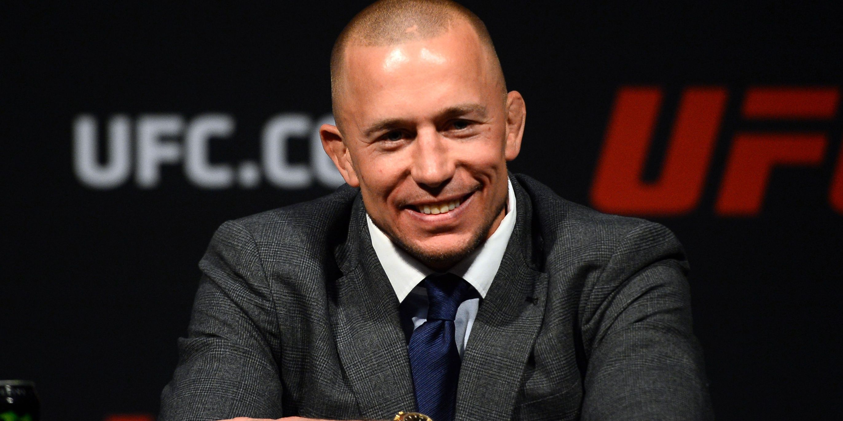 GSP in a suit at a press conference, smiling