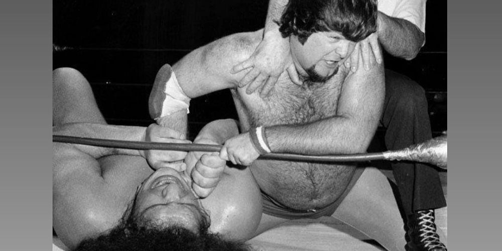 Jerry Lawler choking Andre The Giant on the ground.