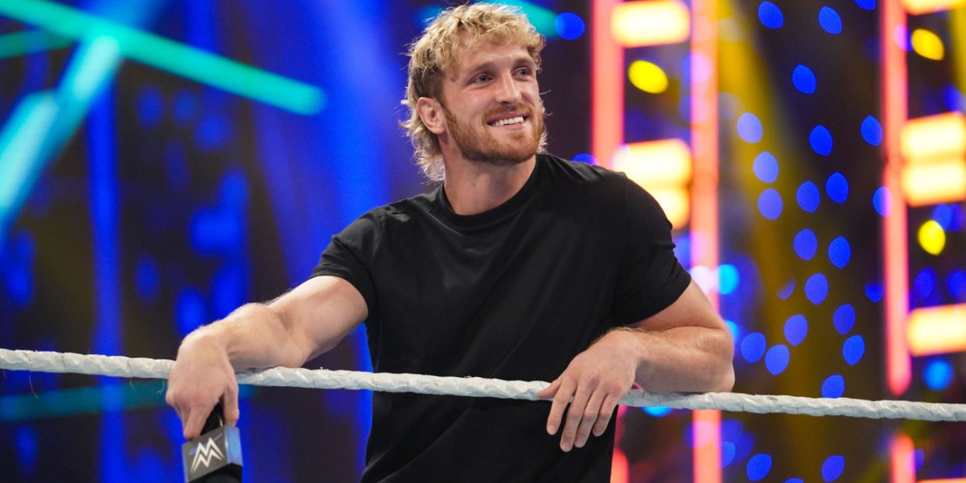 logan paul holding a mic and smiling on the ring apron