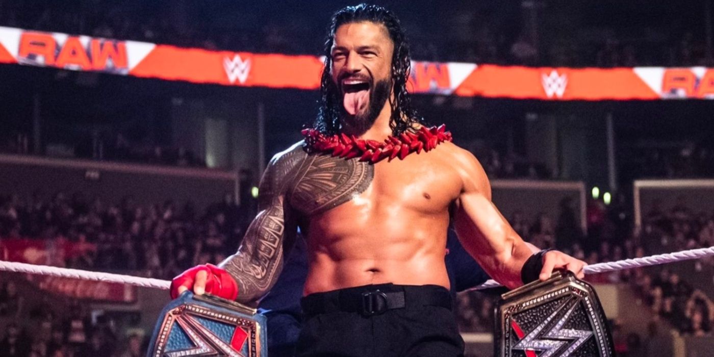 roman reigns with his tongue out, holding the wwe and universal titles