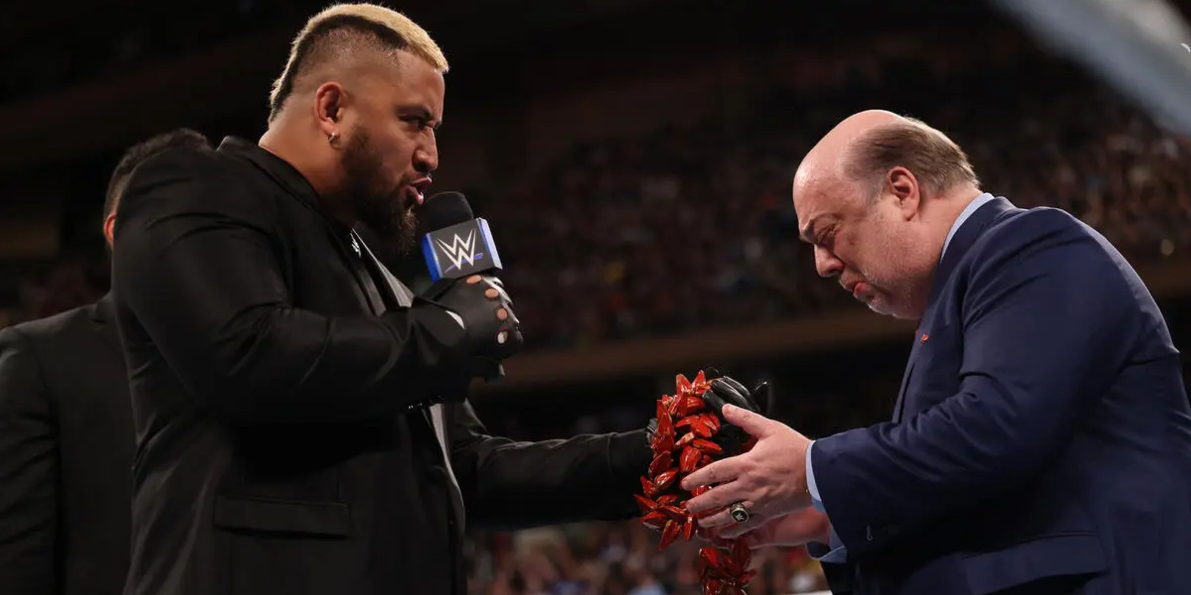 Solo Sikoa presenting Paul Heyman with The Ula Fala.