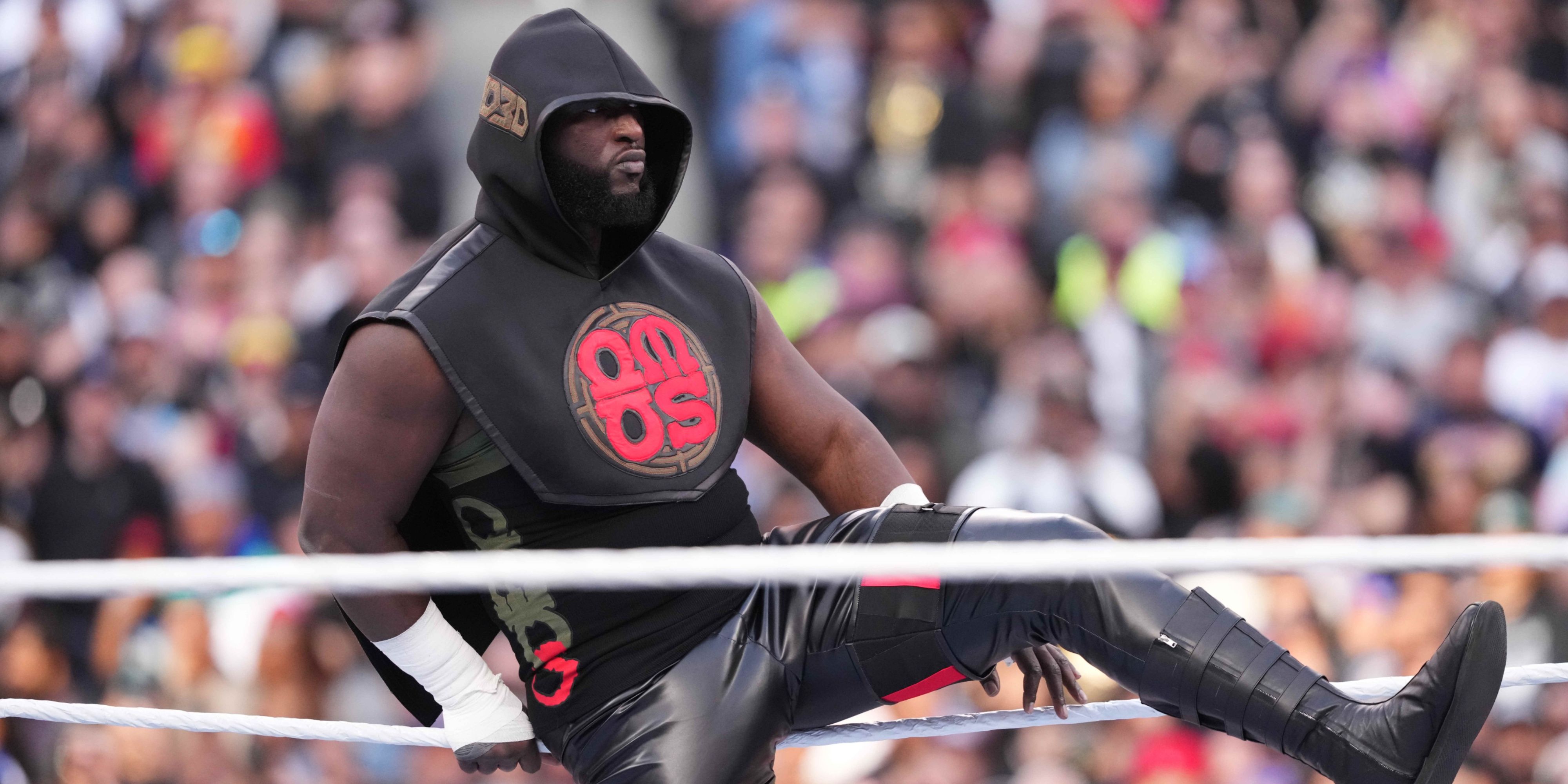 omos stepping over the ropes to get in the ring.