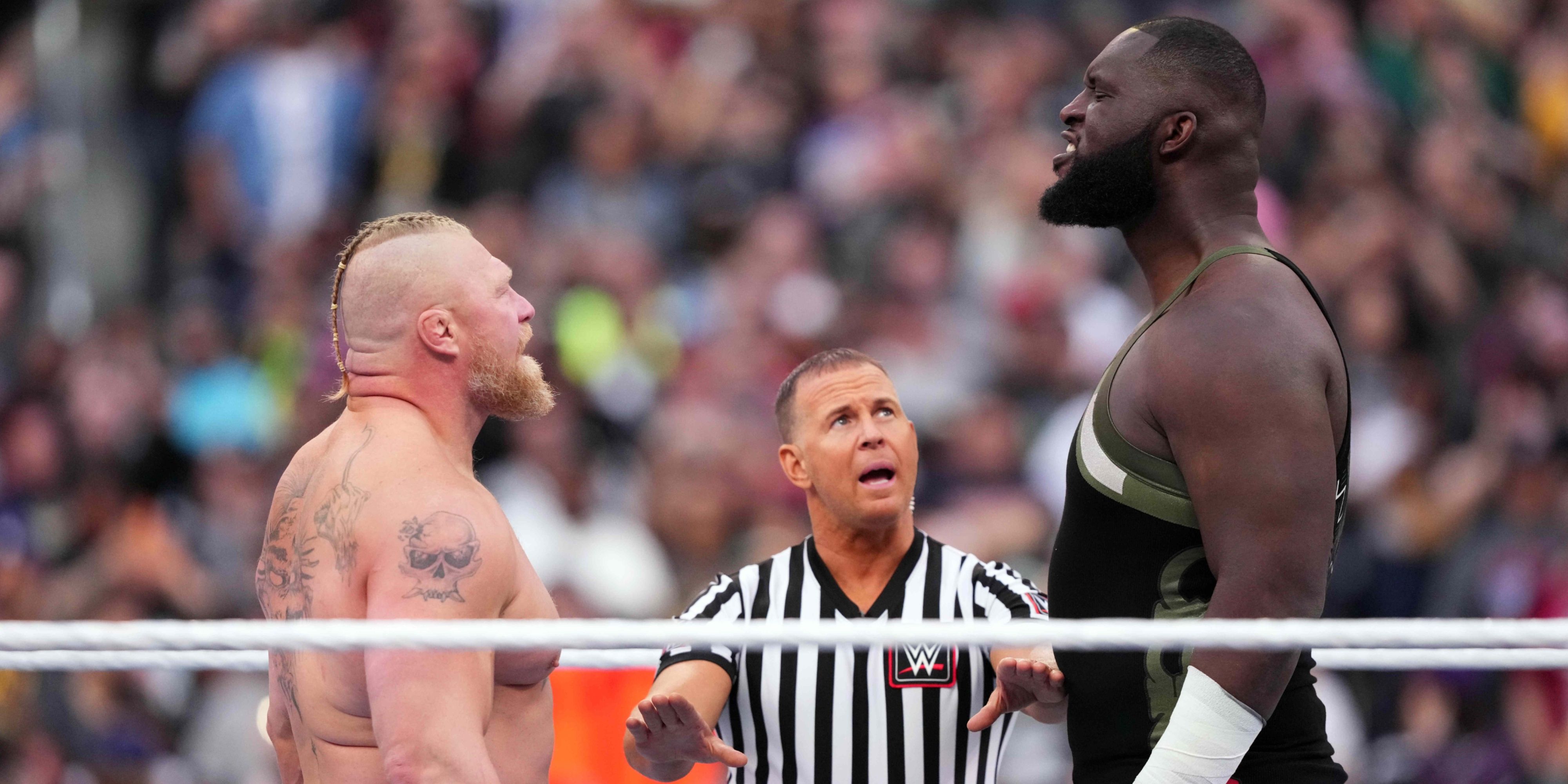 omos standing in the ring with brock lesnar.
