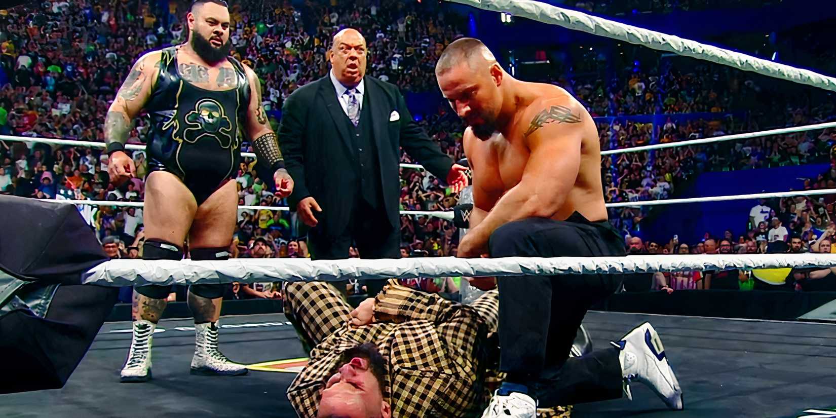 Bron Breakker kneels over Seth Rollins as Bronson Reed and Paul Heyman look on
