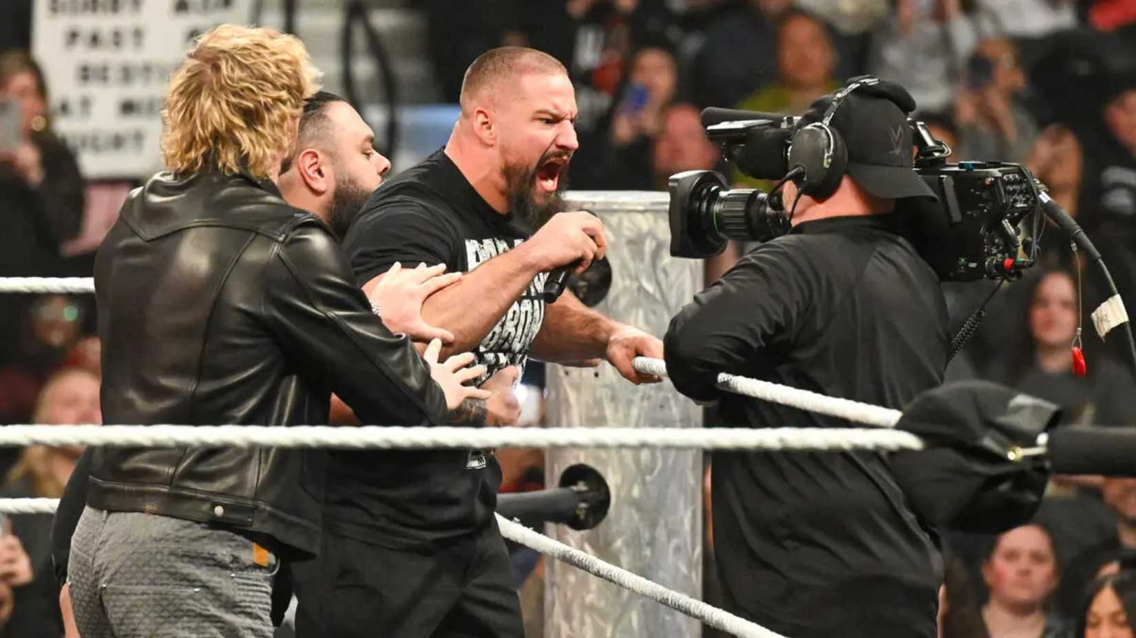 bron breakker being held back as he yells into a camera.