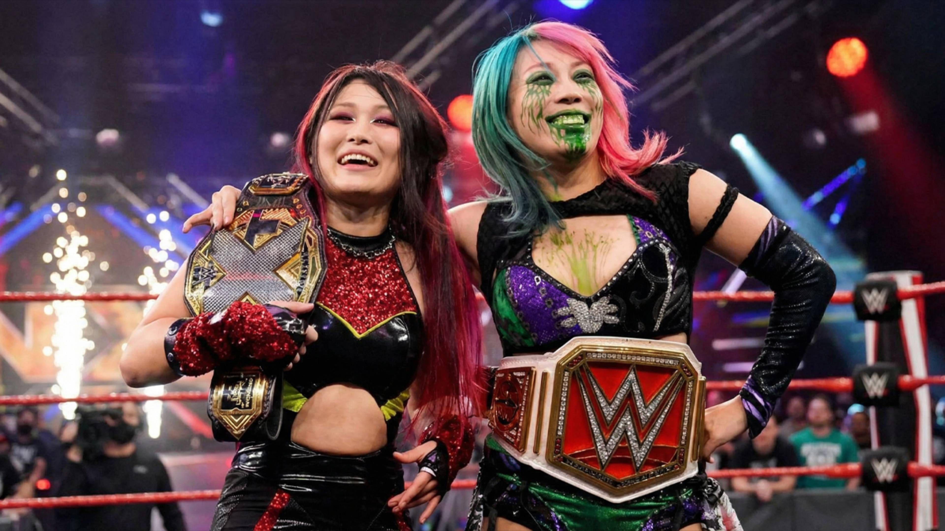 asuka and iyo sky smiling and wearing titles.